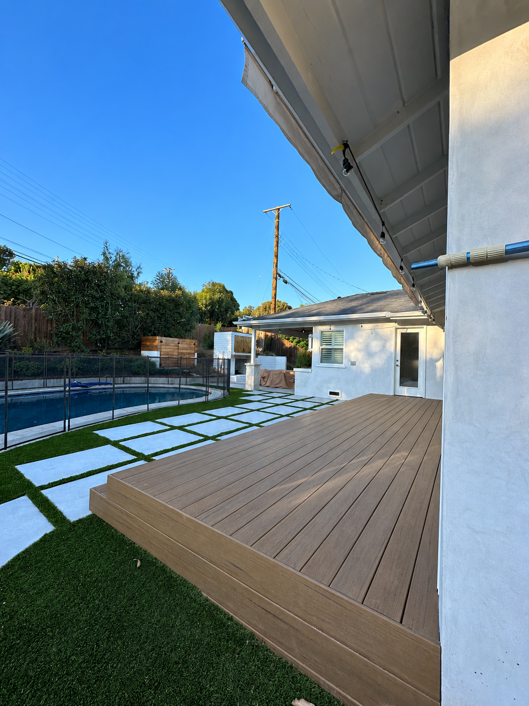 Composite backyard deck beside a pool and landscaped pavers