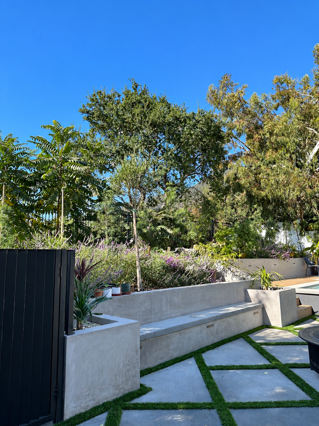 Concrete retaining walls and built-in seating in a landscaped backyard